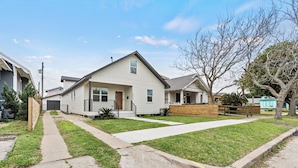 A single-story house with a front yard, a driveway, and a wooden fence. - Modern Lux Home 2 Mins to the Beach+Putting Green
 (Galveston)