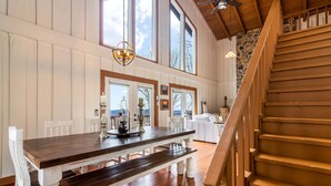 A dining area with a wooden table and benches, a staircase, and a view through the door. - King Bed, Arcade, Hot Tub, Amazing Views (Jasper)
