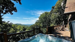 A hot tub on a wooden deck with a view of a forested landscape. - King Bed, Arcade, Hot Tub, Amazing Views (Jasper)