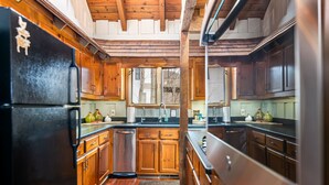 A kitchen with wooden cabinets, stainless steel appliances, and a window providing natural light. - King Bed, Arcade, Hot Tub, Amazing Views (Jasper)