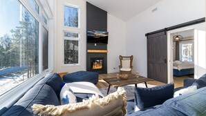 Een moderne woonkamer met een open haard, grote ramen en een gezellige zithoek.