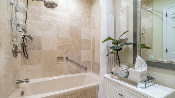 Un baño con bañera, ducha y tocador con espejo.