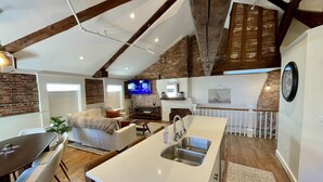 Uma cozinha moderna com uma ilha grande, uma sala de jantar com mesa e cadeiras, e um espaço de estar aconchegante com sofá e televisão.