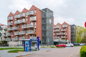 Ein modernes Mehrfamilienhaus mit mehreren Balkonen und einem zentralen Glasaufzug.