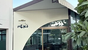 A modern building with a glass entrance, a white exterior, and the name "NEKO" written on the side. - Issara House Bangkok (Bangkok)