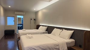 A hotel room with two beds, a bench, a large mirror, and a window. - Issara House Bangkok (Bangkok)