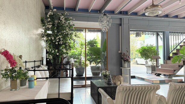 A spacious room with a large window, a black metal gate, and a variety of potted plants. - Issara House Bangkok (Bangkok)