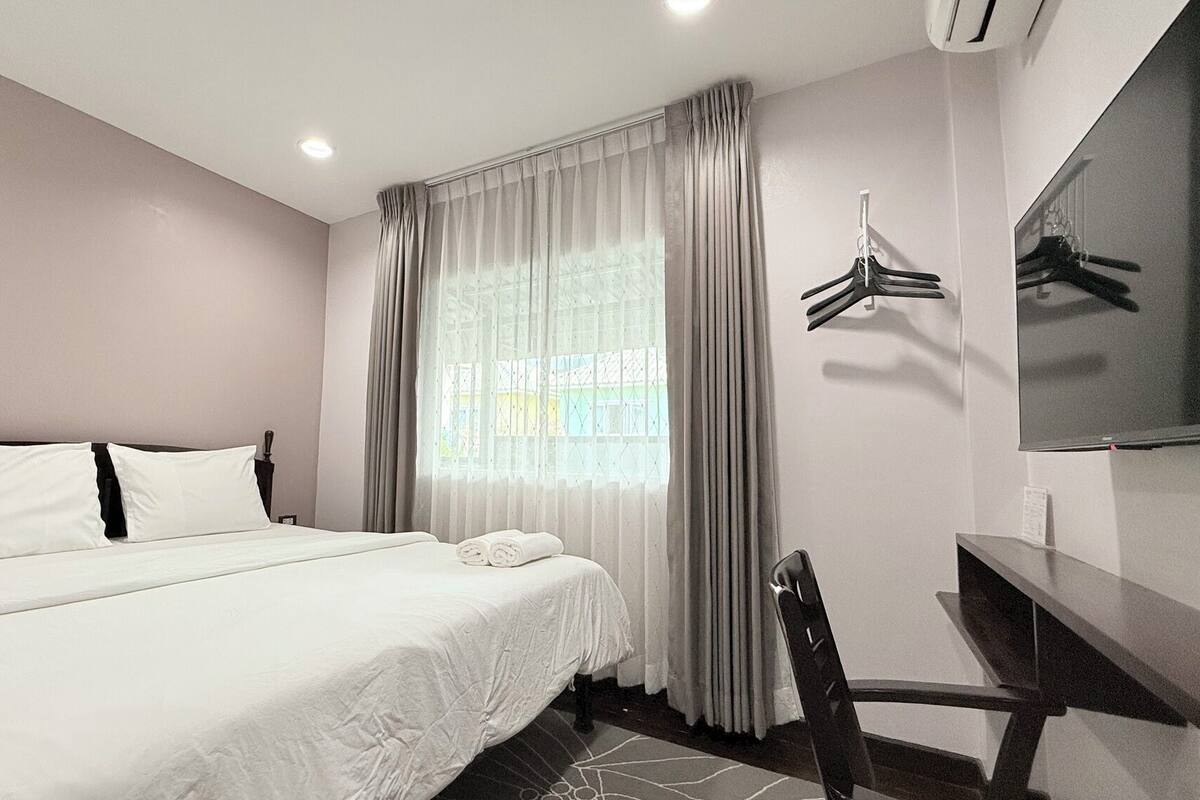 A hotel room with a bed, a desk, a chair, and a TV.