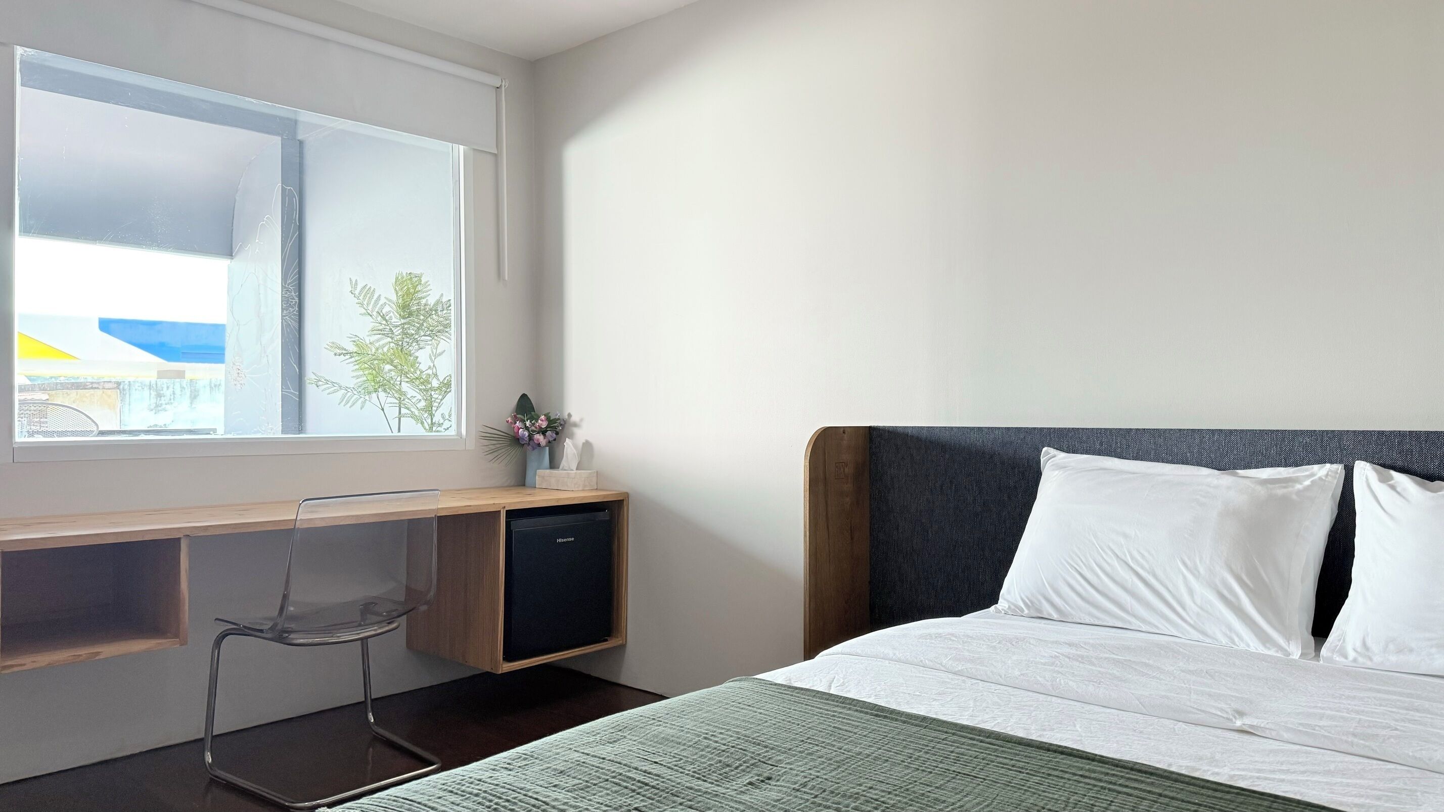 A hotel room with a bed, a desk, and a chair.