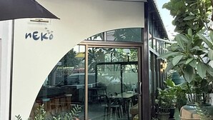 A modern building with a glass entrance, potted plants, and a sign reading "NEKO". - Issara House Bangkok (Bangkok)
