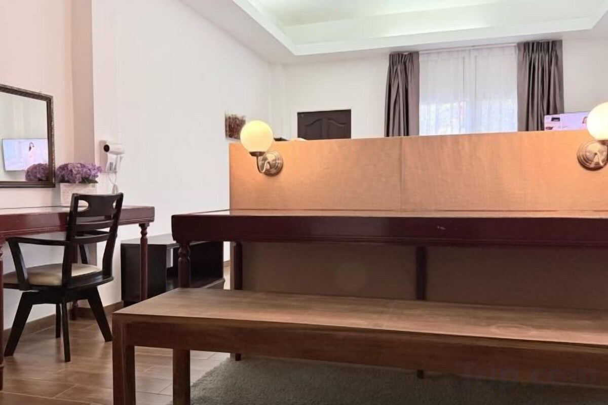 A room with a wooden bench, a dining table with chairs, and a wall-mounted lamp.