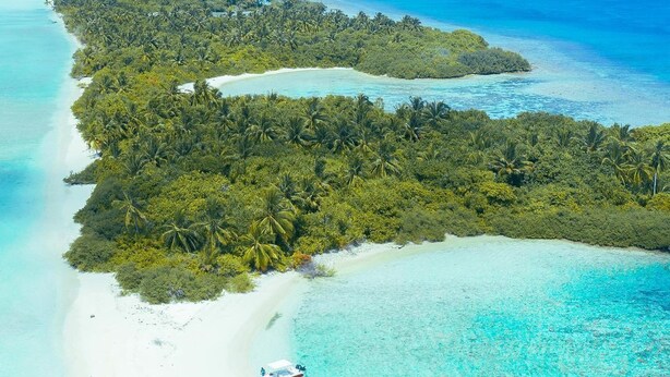 Vue aérienne d’une île tropicale avec ses plages de sable blanc, ses eaux turquoise cristallines et sa végétation luxuriante.