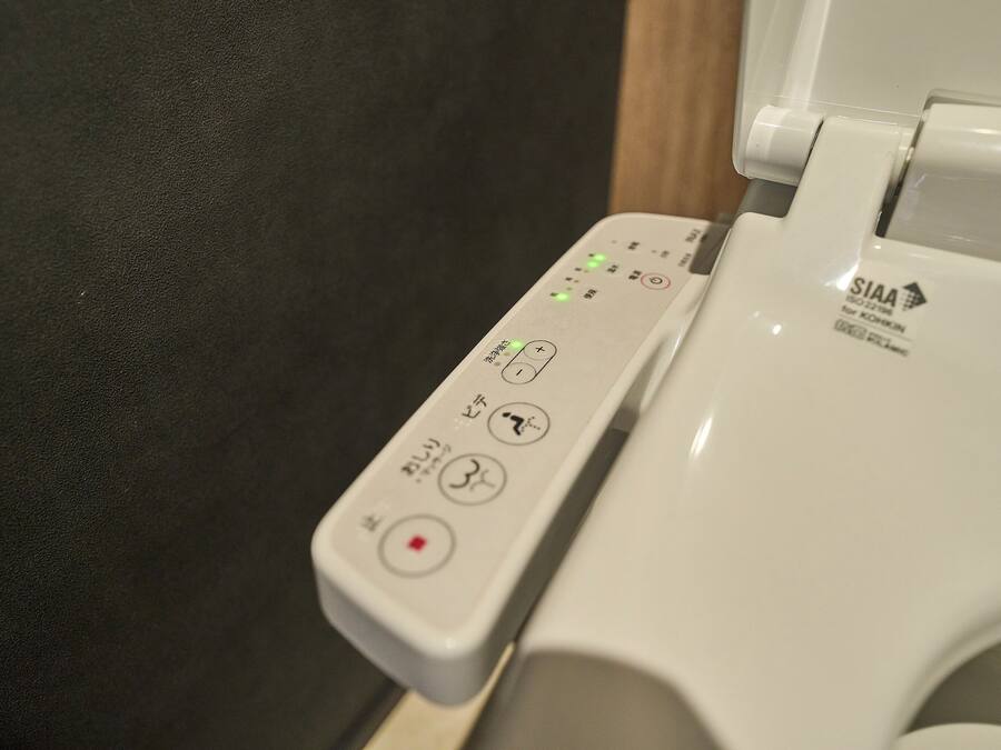 A toilet with a control panel featuring various buttons and indicators.