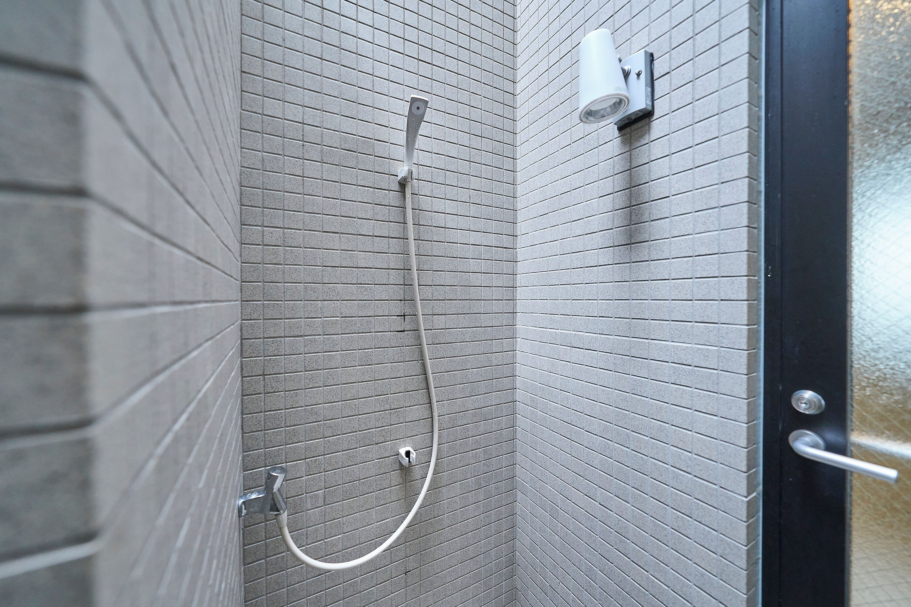 Un área de ducha con paredes de azulejos, un cabezal de ducha y un panel de control.
