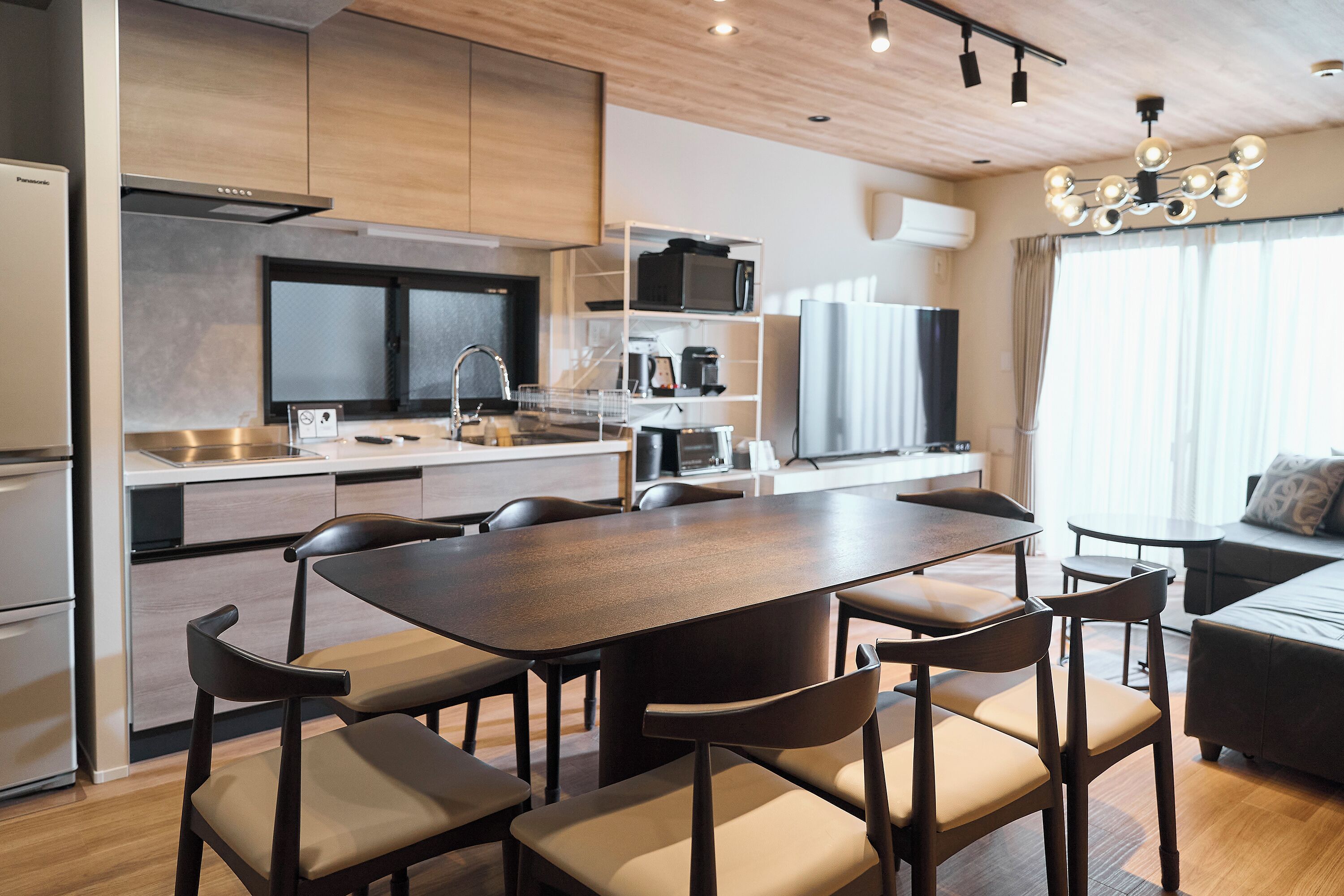 A modern kitchen with a dining area, built-in appliances, and a large window.