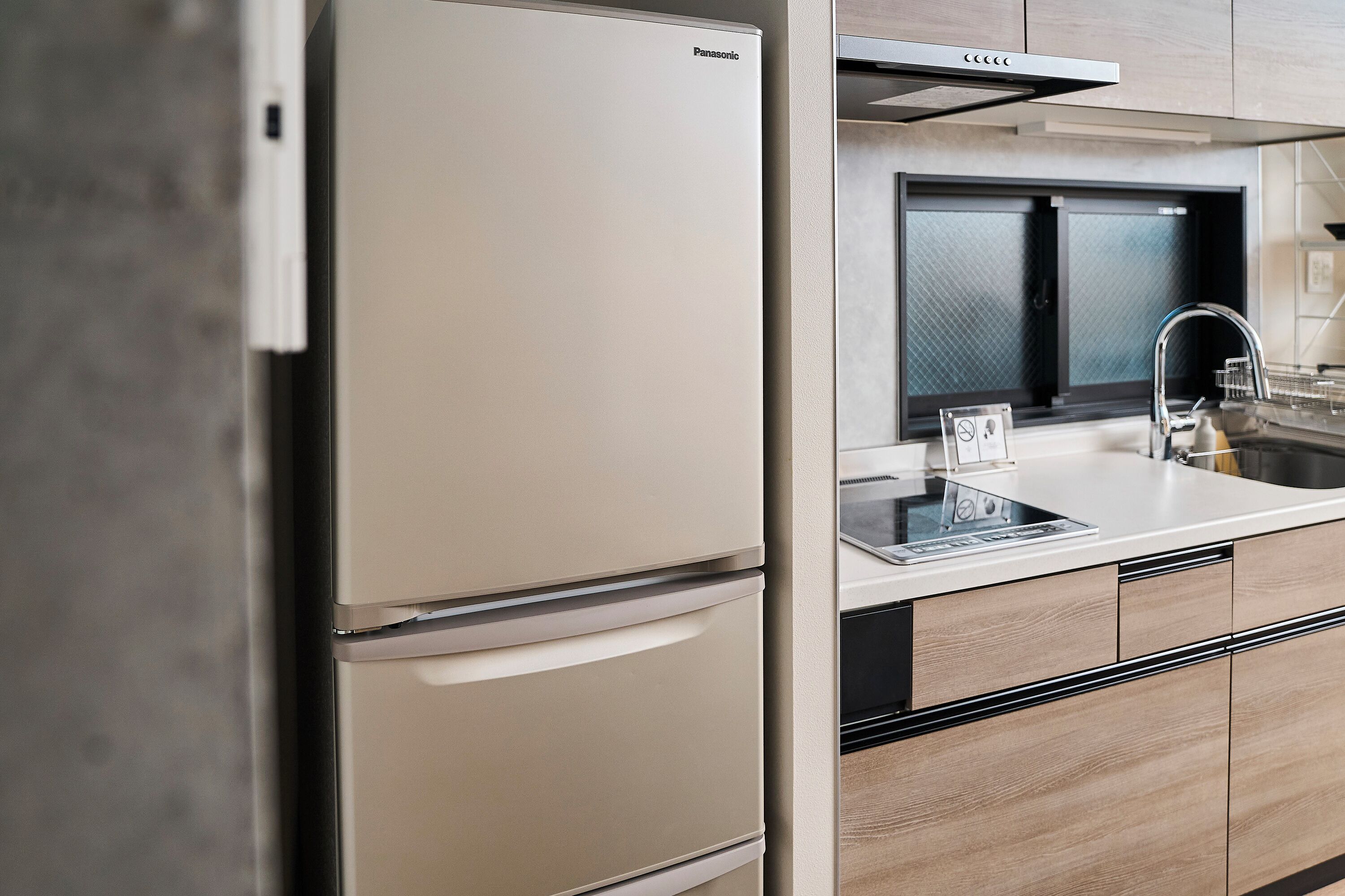 A modern kitchen with a built-in refrigerator, a stainless steel sink, and wooden cabinetry.