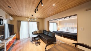 Une chambre d’hôtel moderne avec un plafond en bois, un canapé, une table à manger, un lit et un téléviseur.