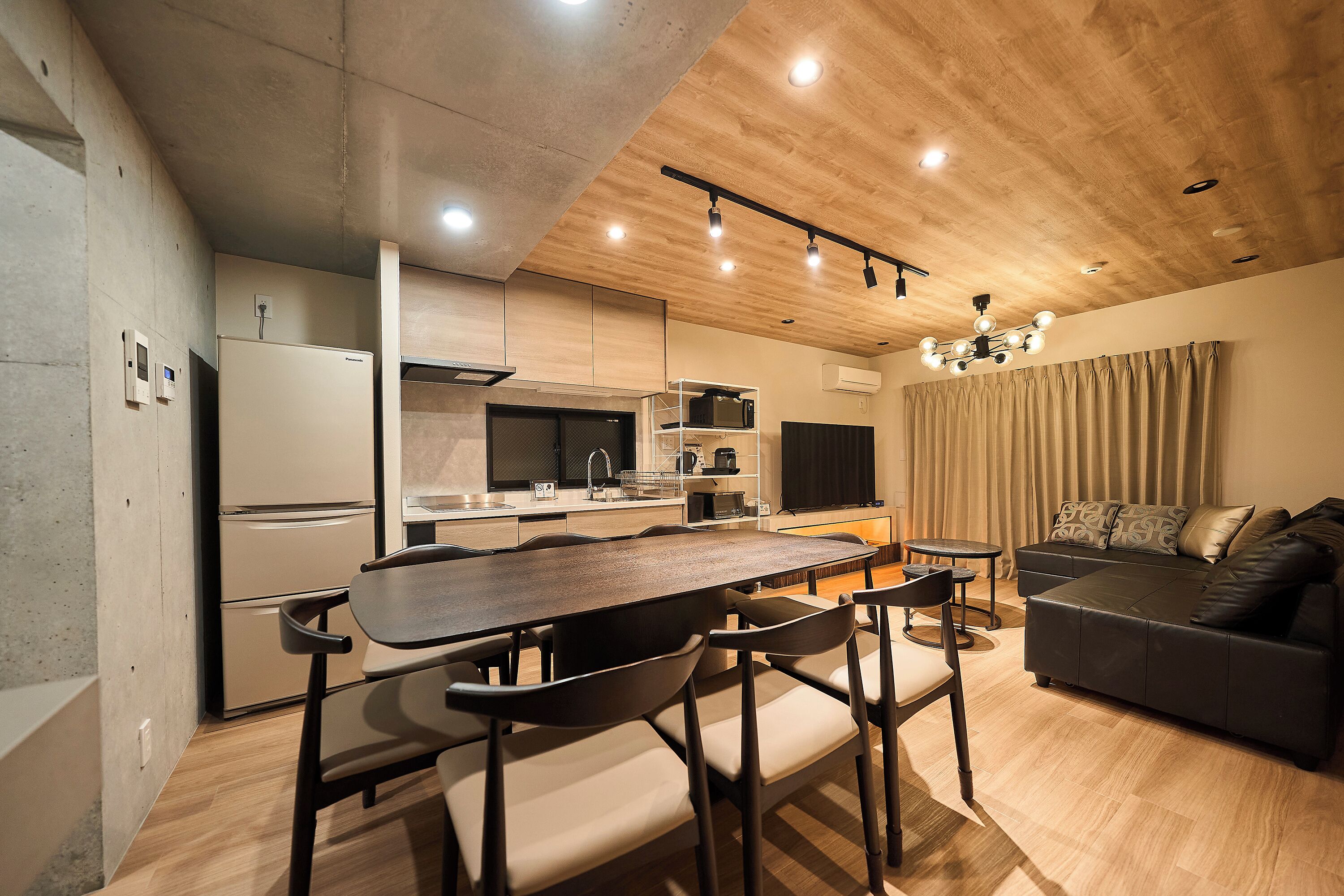 A modern kitchen with a dining area, a sofa, and a chandelier.