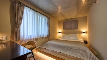Un dormitorio con cama, mesita de noche, silla y ventana con cortinas.