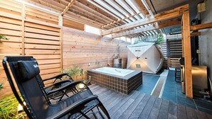 Une terrasse en bois avec un jacuzzi, un barbecue et un espace salon.