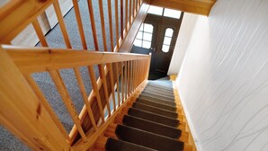 Una scala in legno con gradini rivestiti di tappeto che porta a una porta.