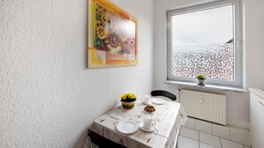 Un'area pranzo con un tavolo apparecchiato per due, una finestra con vista e un quadro appeso al muro.