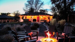 A cozy outdoor seating area with a fire pit, surrounded by Adirondack chairs, and a patio with a view of a house in the background. - Modern Oasis – 6BR Arvada Retreat, Sleeps 14, Hot Tub, Walkable to Olde Town (Arvada)