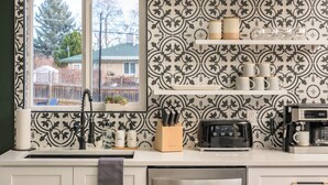A kitchen with patterned wallpaper, a window, a sink, a toaster, and a coffee maker. - Modern Oasis – 6BR Arvada Retreat, Sleeps 14, Hot Tub, Walkable to Olde Town (Arvada)