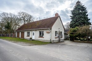 A single-story house with a sloped roof, a front door, and a small porch area. - Apartment 'Kropp' with Private Terrace, Private Garden and Wi-Fi (Knorrendorf)