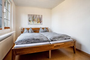 Ein Schlafzimmer mit einem hölzernen Bett, einem Fenster, einer Heizung und einem Bild an der Wand.