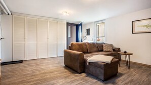 A living room with a sofa, a small table, and a wardrobe. - Apartment 'Kropp' with Private Terrace, Private Garden and Wi-Fi (Knorrendorf)