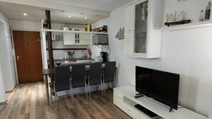 Una cocina moderna con comedor, televisor y un mueble blanco.