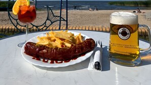 Ein Tisch mit einem Teller Essen, einem Bierkrug und einem Getränk mit Orangenscheibe.