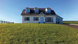 A two-story house with a sloped roof, a front porch, and a fenced yard.