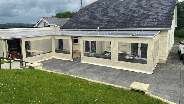 A house with a sloped roof, a covered patio area, and a small garden.