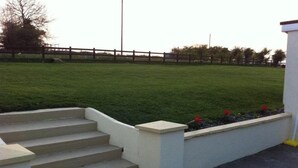 A set of concrete steps leading to a white wall with a flower bed.