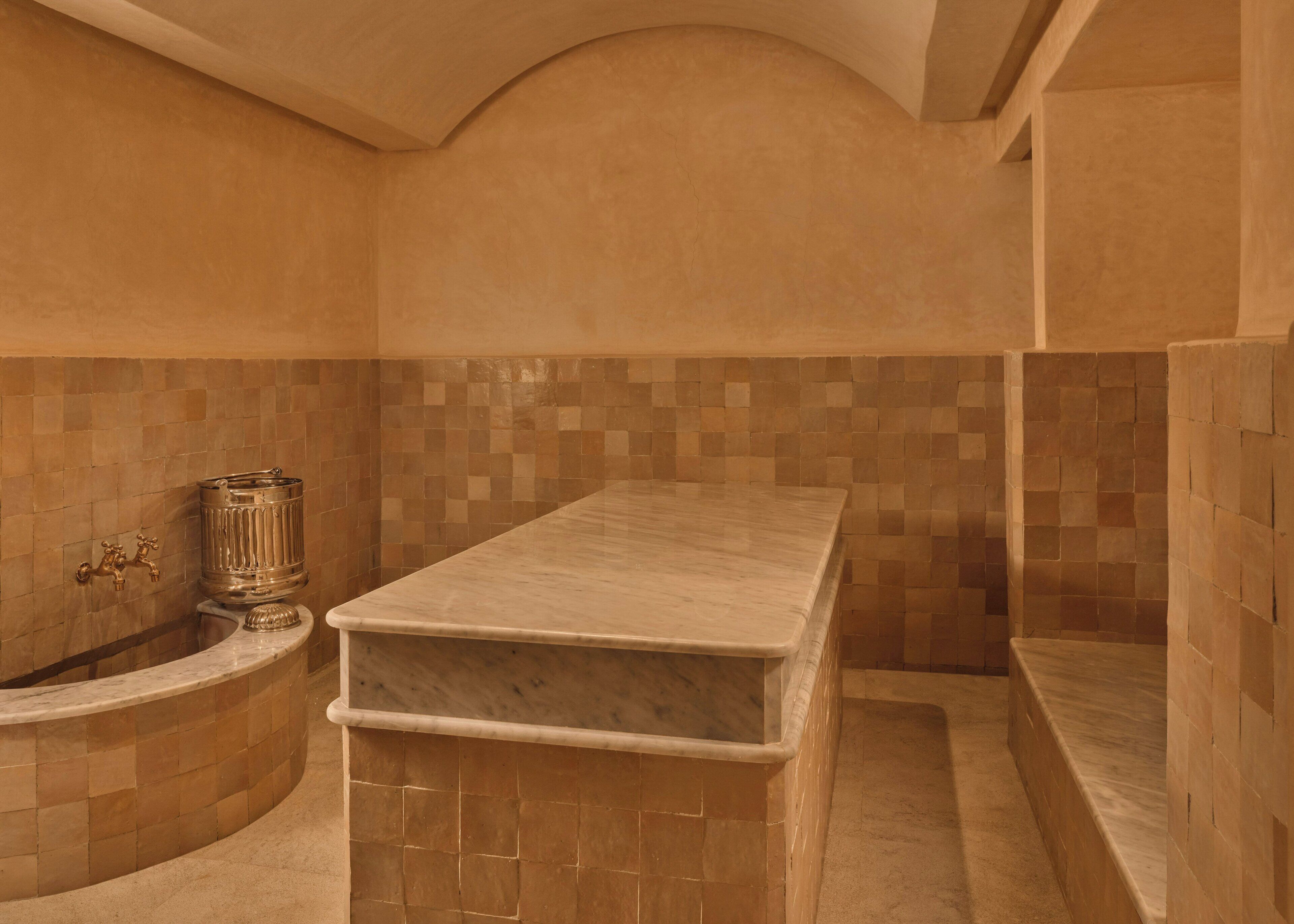 A bathroom with a marble countertop, a tiled wall, and a curved bathtub.