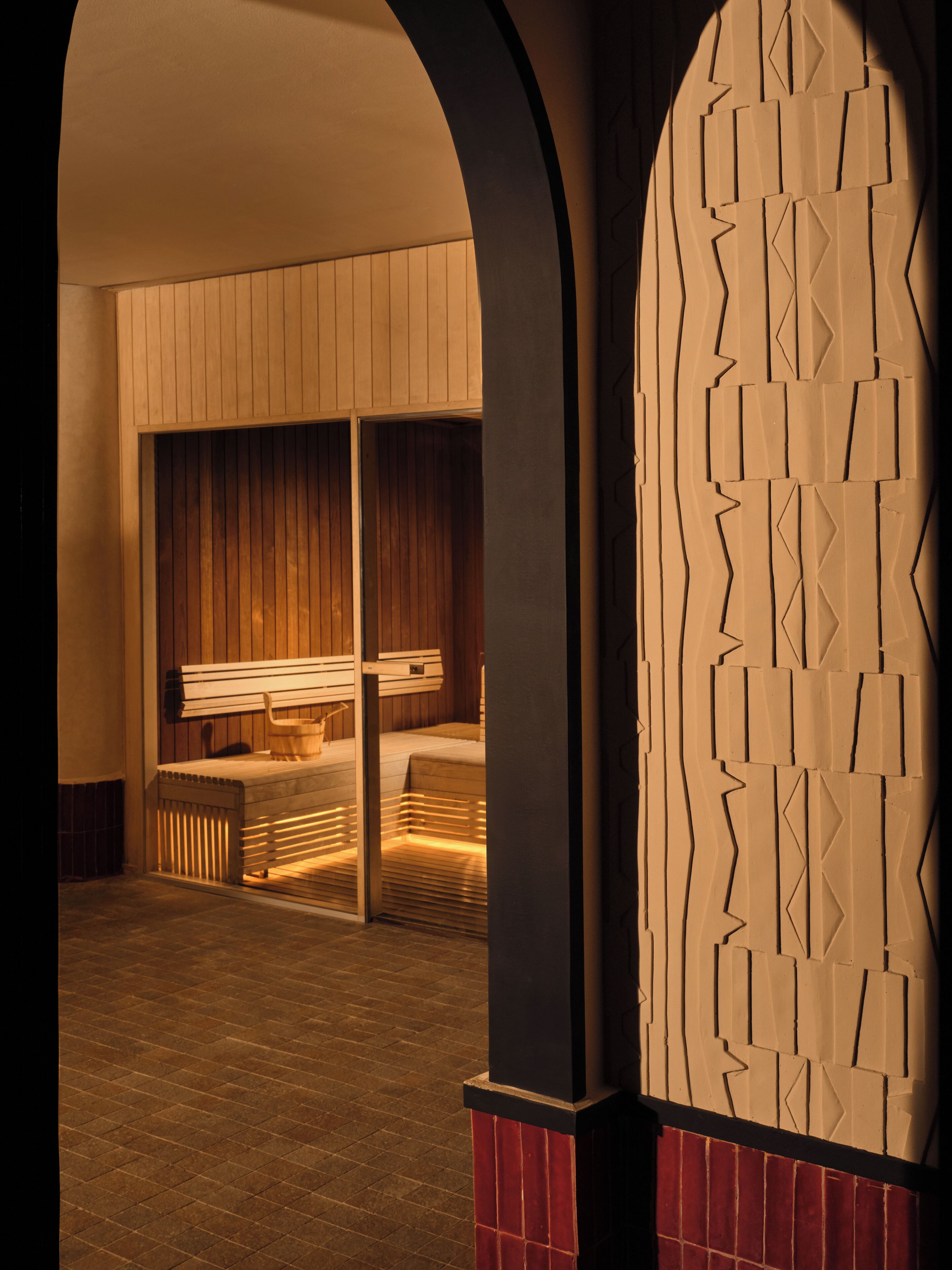 Un cuarto de spa con un banco de madera, una camilla de masaje y un muro con diseño.
