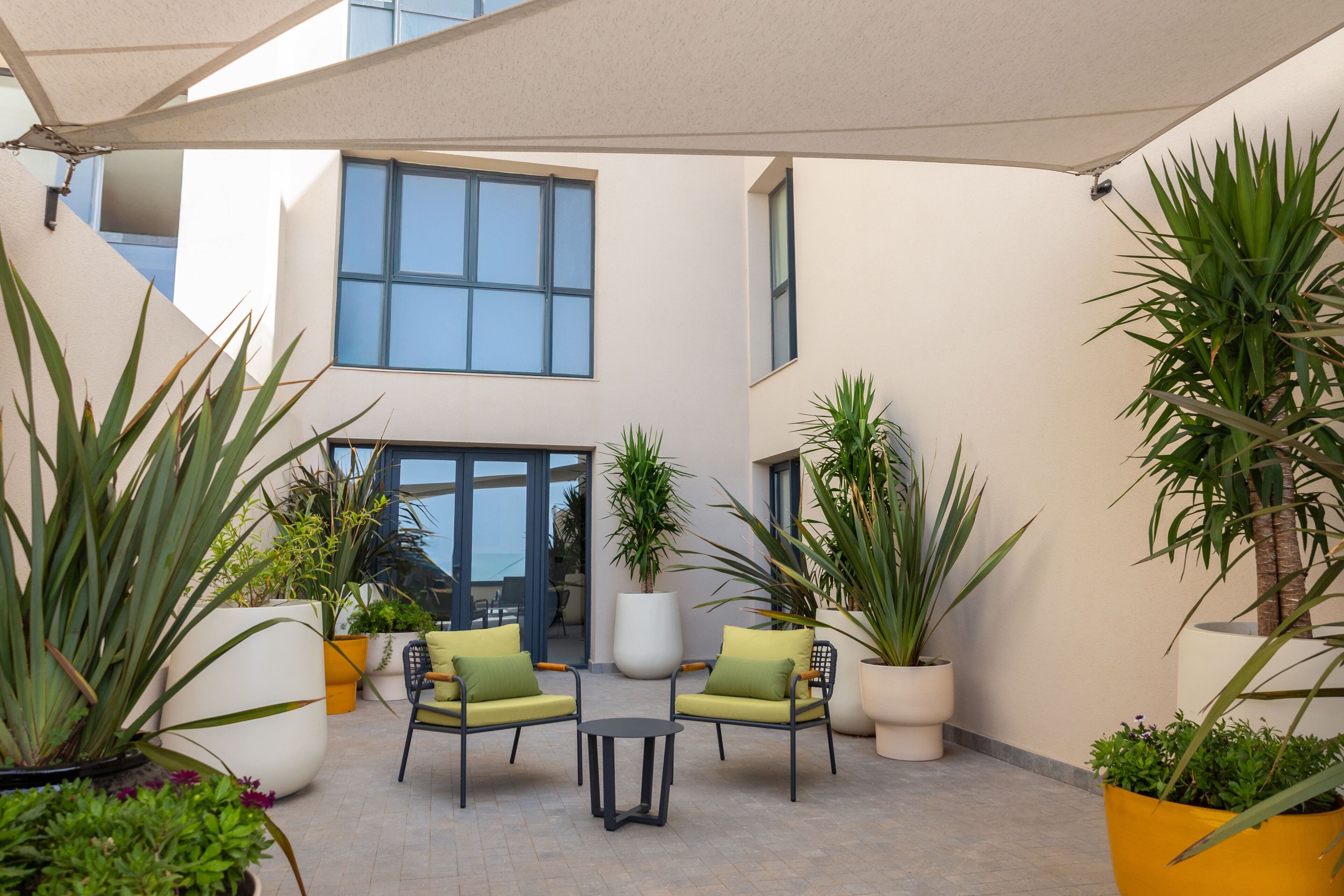 Une cour avec des sièges en plein air, des plantes en pot et un bâtiment en arrière-plan.