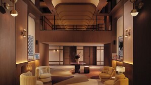 Eine geräumige Lobby mit hoher Decke, moderner Möblierung und einem runden Tisch in der Mitte mit einer Vase.