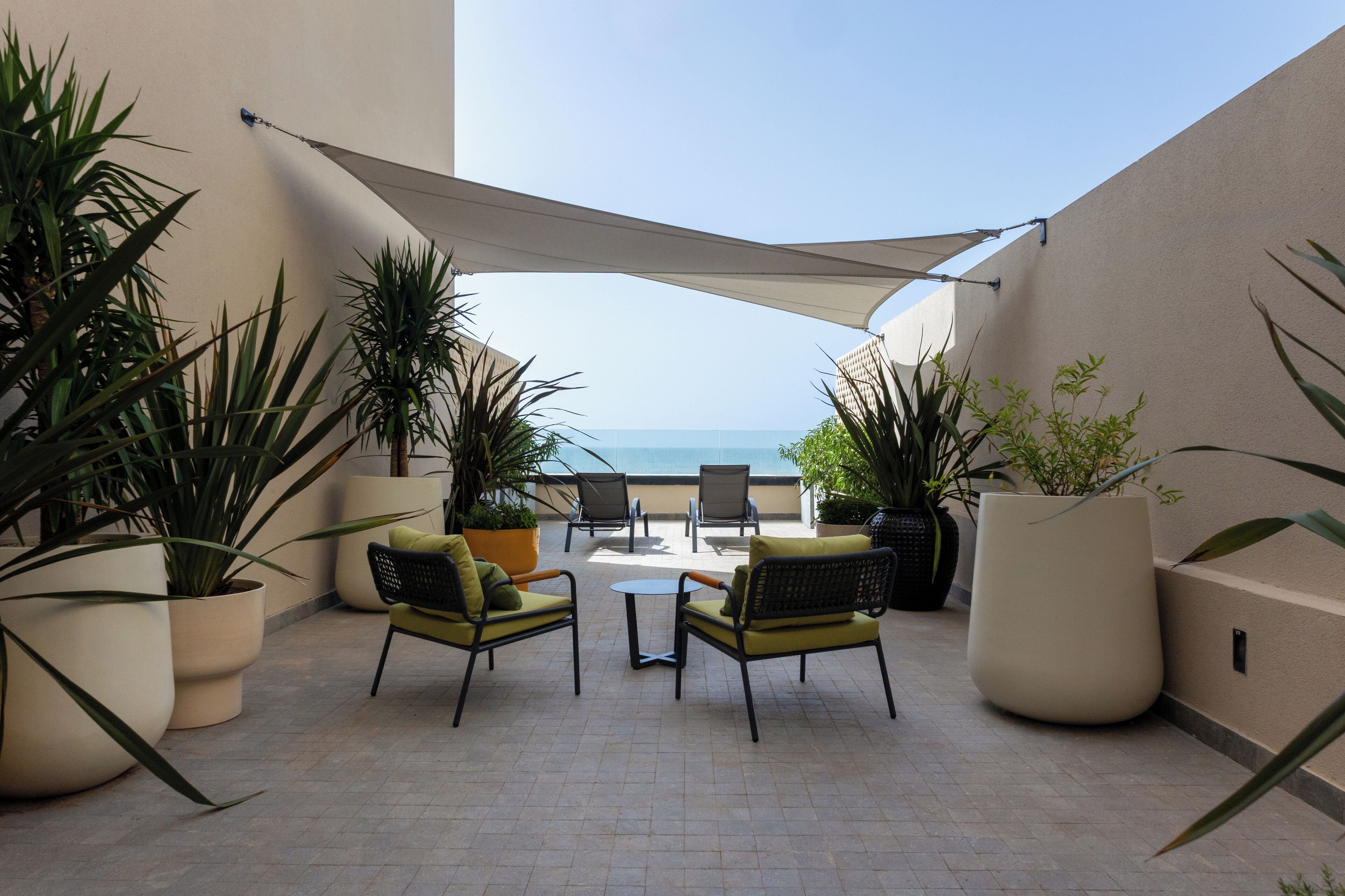 A terrace with outdoor seating, potted plants, and a view of the sea.