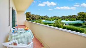 A balcony with a table set for dining, a chair, and a bottle of water.