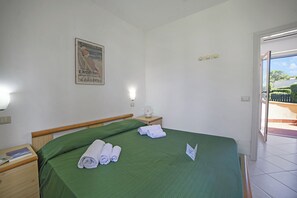 A hotel room with a bed, a nightstand, a poster on the wall, and a view of the outside. - Le Onde Apartment 1 with Pool n.114/a, Otranto, Italy (Otranto)