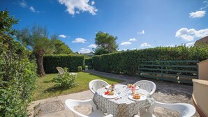 A round table with white chairs set outdoors, surrounded by greenery and a clear sky. - Le Onde Apartment 1 with Pool n.114/a, Otranto, Italy (Otranto)