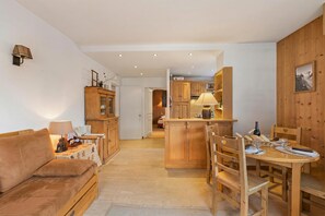 A cozy living room with a sofa, a dining table with chairs, wooden cabinets, and a kitchen area with a counter and cabinets.