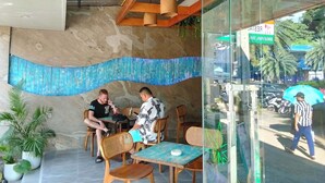 Un espace extérieur aménagé avec des tables et des chaises en bois, un mur en pierre et des plantes en pot.