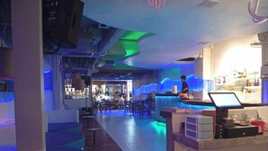 Un espace bar avec un comptoir, des sièges et un barman.