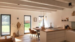 Una cucina moderna con isola centrale, pavimento in legno e luci a sospensione.
