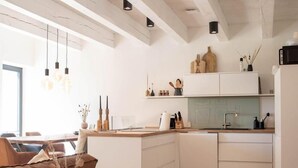 Una cucina moderna con mobili bianchi, travi in legno e lampade a sospensione.