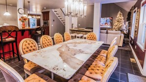 Un espace repas avec une table en marbre, des chaises rembourrées et un lustre.